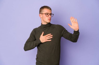 Beyaz tenli yakışıklı bir adam yemin ediyor, elini göğsüne koyuyor..