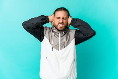 Uzun saçlı genç adam elleriyle kulaklarını kapatıyor..