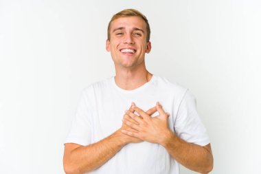 Genç, beyaz, yakışıklı bir adam gülüyor. Elini yüreğine koyuyor. Mutluluk kavramı..