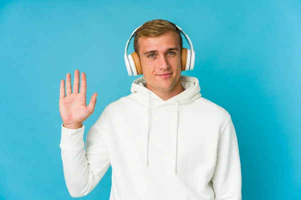 Jovem Caucasiano Homem Ouvindo Música Isolada Fundo Azul Sorrindo Alegre — Fotografia de Stock