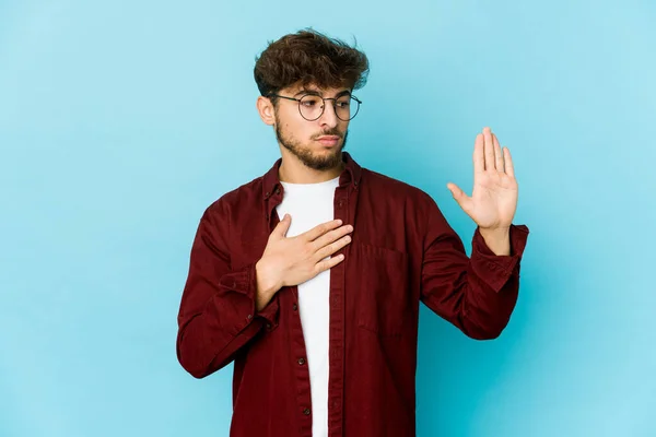 Jovem Árabe Homem Fundo Azul Fazendo Juramento Colocando Mão Peito — Fotografia de Stock