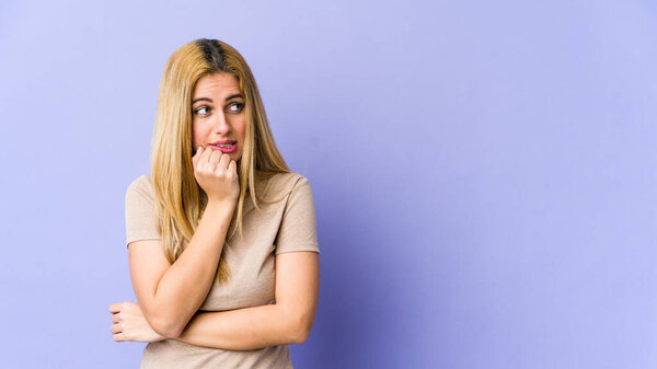Young blonde caucasian woman biting fingernails, nervous and very anxious.