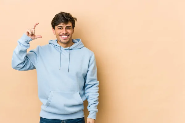 Mladý Cool Muž Drží Něco Málo Ukazováčky Usmívá Sebevědomě — Stock fotografie