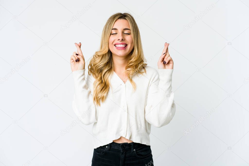 Young caucasian blonde woman crossing fingers for having luck