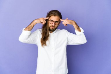 Uzun saçlı genç adam bir işe odaklanmış görünüyor, işaret parmaklarını işaret ediyor..