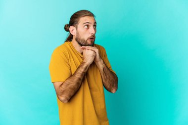 Uzun saçlı genç adam şans için dua ediyor, şaşırmış ve ağzını açıyor..