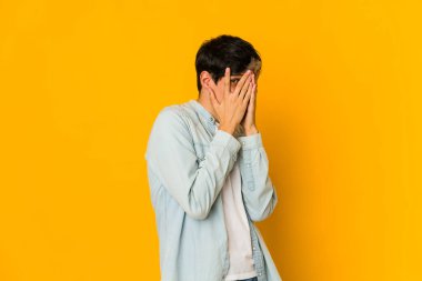 Genç, sıska, ispanyol bir adam parmaklarının arasından korkmuş ve gergin bir şekilde göz kırpıyor..