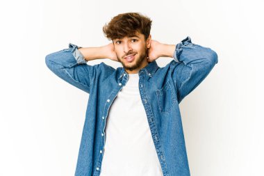 Beyaz arka plandaki genç Arap adam kafasının arkasına dokunuyor, düşünüyor ve bir seçim yapıyor..