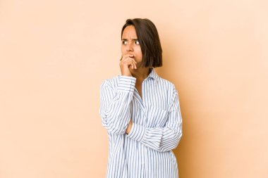 Latin kökenli genç bir kadın, elleri endişeli bir şekilde ağzını kapatıyor..