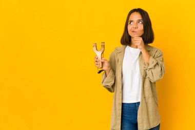 Genç İspanyol kadın elinde sapanla şüpheli ve şüpheci bir ifadeyle yana bakıyor..