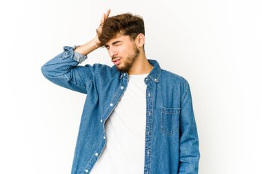 Beyaz arka planda genç bir Arap bir şeyi unutuyor. Alnına avuç içi ve kapalı gözlerle vuruyor..