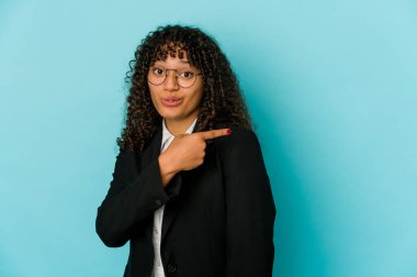 Genç Afrikalı Afro-Amerikan kadın izole edilmiş gülümseyen ve işaret eden, boş bir alanda bir şey gösteriyor.