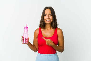Beyaz arka planda izole edilmiş bir milkshake tutan genç Latin kadın işaret parmağıyla fotokopi alanını işaret ederek şok oldu..