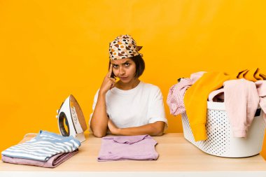 Giysileri ütüleyen genç İspanyol kadın, tecrit edilmiş, parmağıyla işaret eden, düşünen, bir göreve odaklanmış..