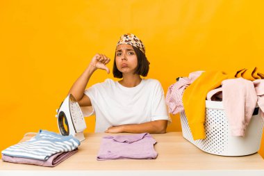 Giysilerini ütüleyen genç İspanyol kadın hoşlanmadığı bir jest yapıyor, kabul etmiyor. Anlaşmazlık konsepti.