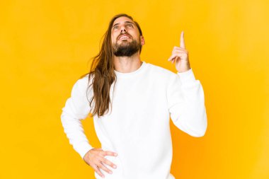 Uzun saçlı genç adam ön parmakları havada boş bir yer gösteriyor..