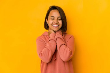 Genç İspanyol kadın sarıda izole edilmiş, kendinden emin, elleri başının arkasında..