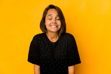 Genç İspanyol kadın sarıda izole edilmiş, gülüyor, gözlerini kapatıyor, rahatlamış ve mutlu hissediyor..