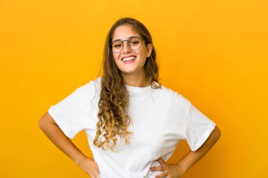 Genç beyaz kadın kendine güveniyor, ellerini kalçasında tutuyor..