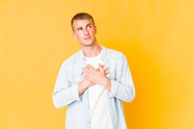 Beyaz tenli yakışıklı bir adam dost canlısı bir ifadeye sahip, avuçlarını göğsüne bastırıyor. Aşk konsepti.