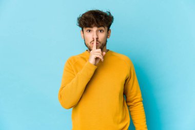 Mavi arka plandaki genç Arap ya sır saklıyor ya da sessizlik istiyor..