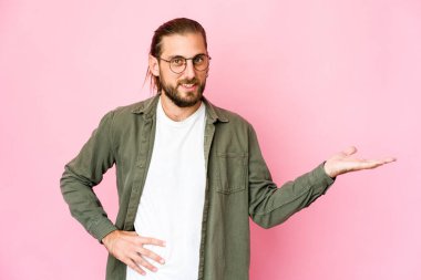 Uzun saçlı genç adam avucunun içinde fotokopi odası gösteriyor ve belinde bir el daha tutuyor..