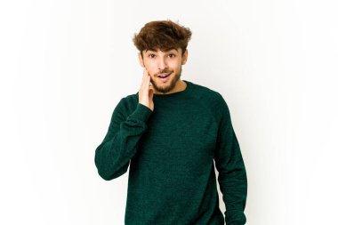 Beyaz arka plandaki genç Arap yüksek sesle bağırıyor, gözleri açık ve elleri gergin tutuyor..