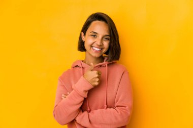 Genç İspanyol kadın sarıda izole edilmiş gülümsüyor ve başparmağını kaldırıyor.