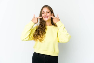 Genç beyaz kadın gülümsüyor, parmaklarıyla ağzını işaret ediyor..