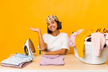 Giysileri ütüleyen genç İspanyol kadın bir avuç içinde fotokopi alanı gösteriyor ve belinde başka bir el tutuyor..