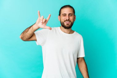 Uzun saçlı genç adam boynuzlarını gösteriyor devrim konsepti olarak jest yapıyor..