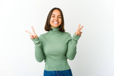 Genç melez kadın zafer işareti gösteriyor ve gülümsüyor..