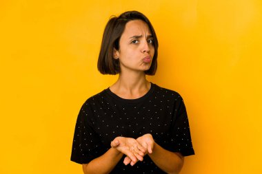 Sarı kıvrımlı dudaklarda izole edilmiş genç İspanyol kadın ve hava öpücüğü göndermek için avuç içleri tutuyor..