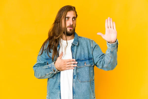 Uzun saçlı genç adam yemin ediyor, elini göğsüne koyuyor..