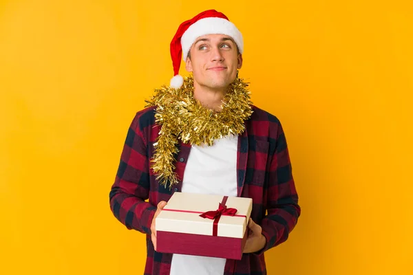 Junger Kaukasischer Mann Mit Weihnachtsmütze Hält Ein Geschenk Isoliert Auf — Stockfoto