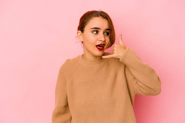 Young arab mixed race woman showing a mobile phone call gesture with fingers.