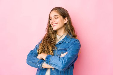 Genç beyaz kadın kollarını kavuşturarak gülümsüyor..