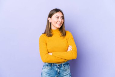 Genç beyaz kadın kollarını kavuşturarak gülümsüyor..