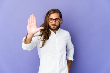 Uzun saçlı genç adam gülümsüyor. Beş numarayı parmaklarıyla gösteriyor..