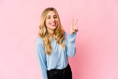 Beyaz tenli sarışın kadın başparmağıyla işaret ediyor, gülüyor ve kaygısız..