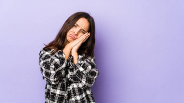 Genç, Latin kökenli bir kadın kendini izole etmiş esniyor. Ağzıyla ağzını kapatan yorgun bir hareket sergiliyor..