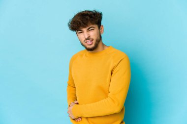 Mavi arka planda genç bir Arap adamın karaciğeri ağrıyor, karnı ağrıyor..