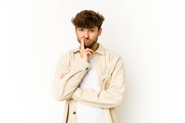 Beyaz arka plandaki genç Arap adam iğneleyici bir ifadeyle kameraya bakarken mutsuz oluyor..