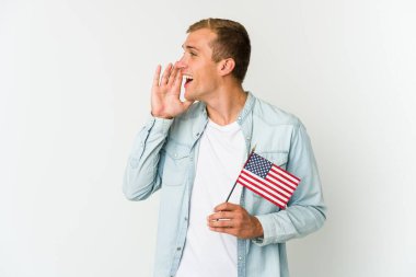 Beyaz arka planda izole edilmiş Amerikan bayrağı tutan genç beyaz bir adam bağırıyor ve avuç içini açık tutuyor..