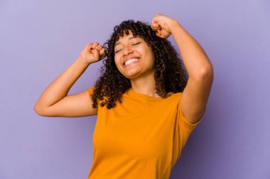 Genç Afrikalı Afro-Amerikalı kadın özel bir günü kutluyor, atlıyor ve enerjisiyle kollarını kaldırıyor..