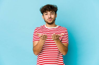 Mavi arka planda genç bir Arap dudaklarını katlıyor ve hava öpücüğü göndermek için avuç içleri tutuyor..