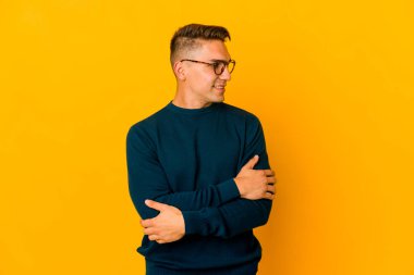 Genç, yakışıklı, beyaz, soyutlanmış, kendine güvenen, kollarını kavuşturmuş bir adam..