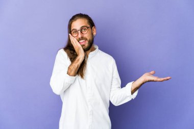 Uzun saçlı genç adam avucunda fotokopi alanı tutuyor, el üstünde tutuyor. Şaşırmış ve mutlu..