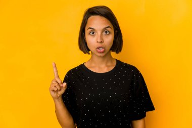 Sarıya izole edilmiş, ağzı açık, üst tarafı işaret eden genç İspanyol kadın..