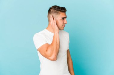 Beyaz tenli yakışıklı bir adam bir dedikoduyu dinlemeye çalışıyor..